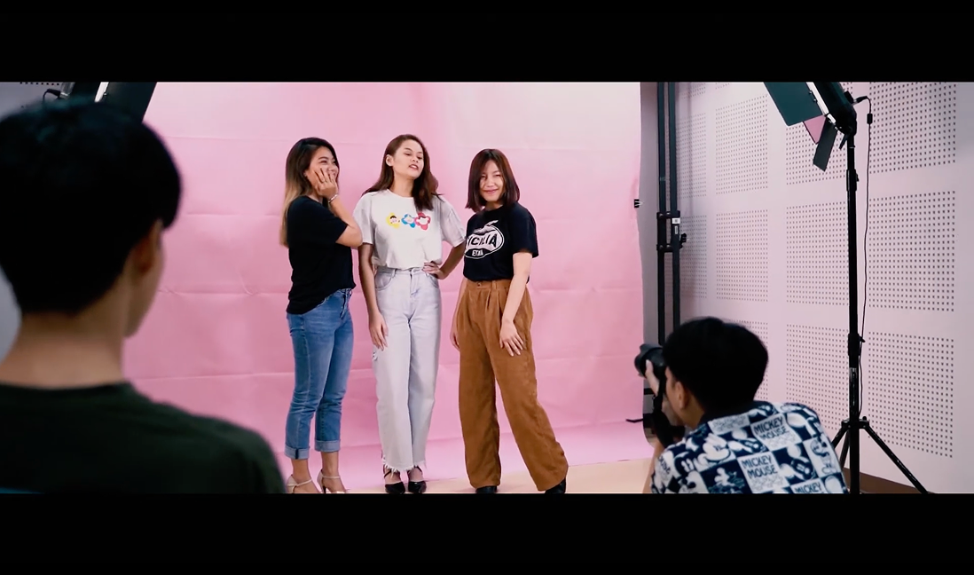 Behind the scenes — three women posing in front of the pink backdrop