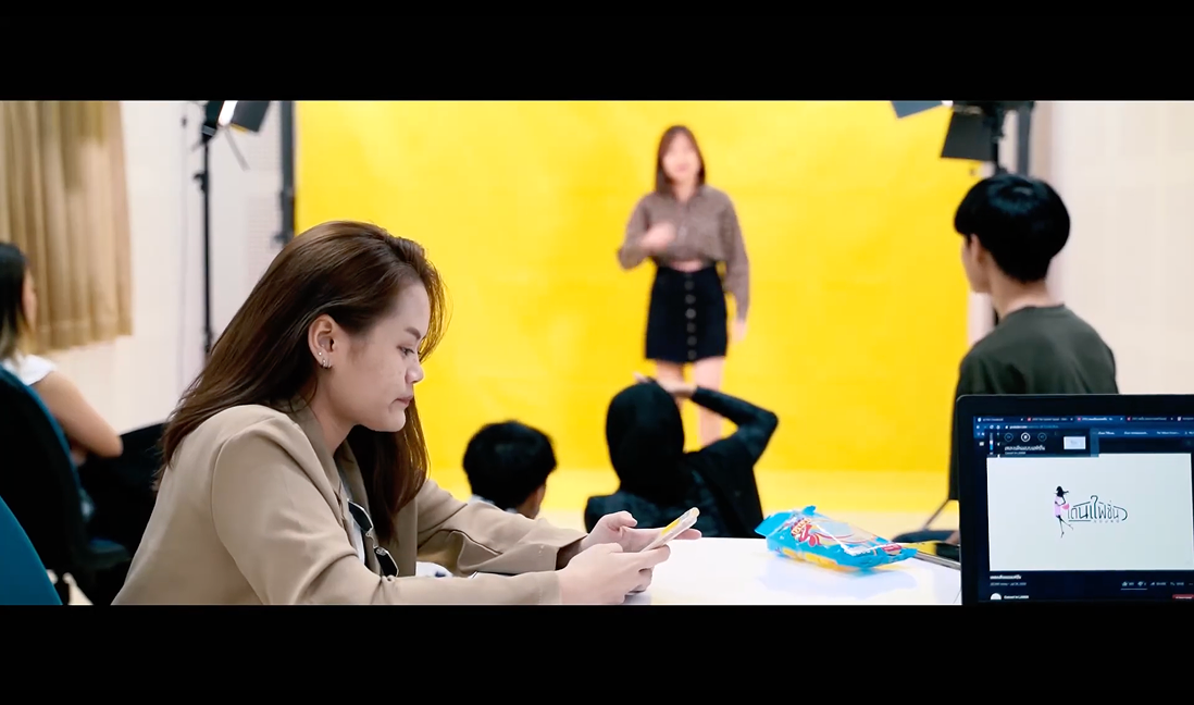 Behind the scenes — crew watching the model pose against the yellow backdrop