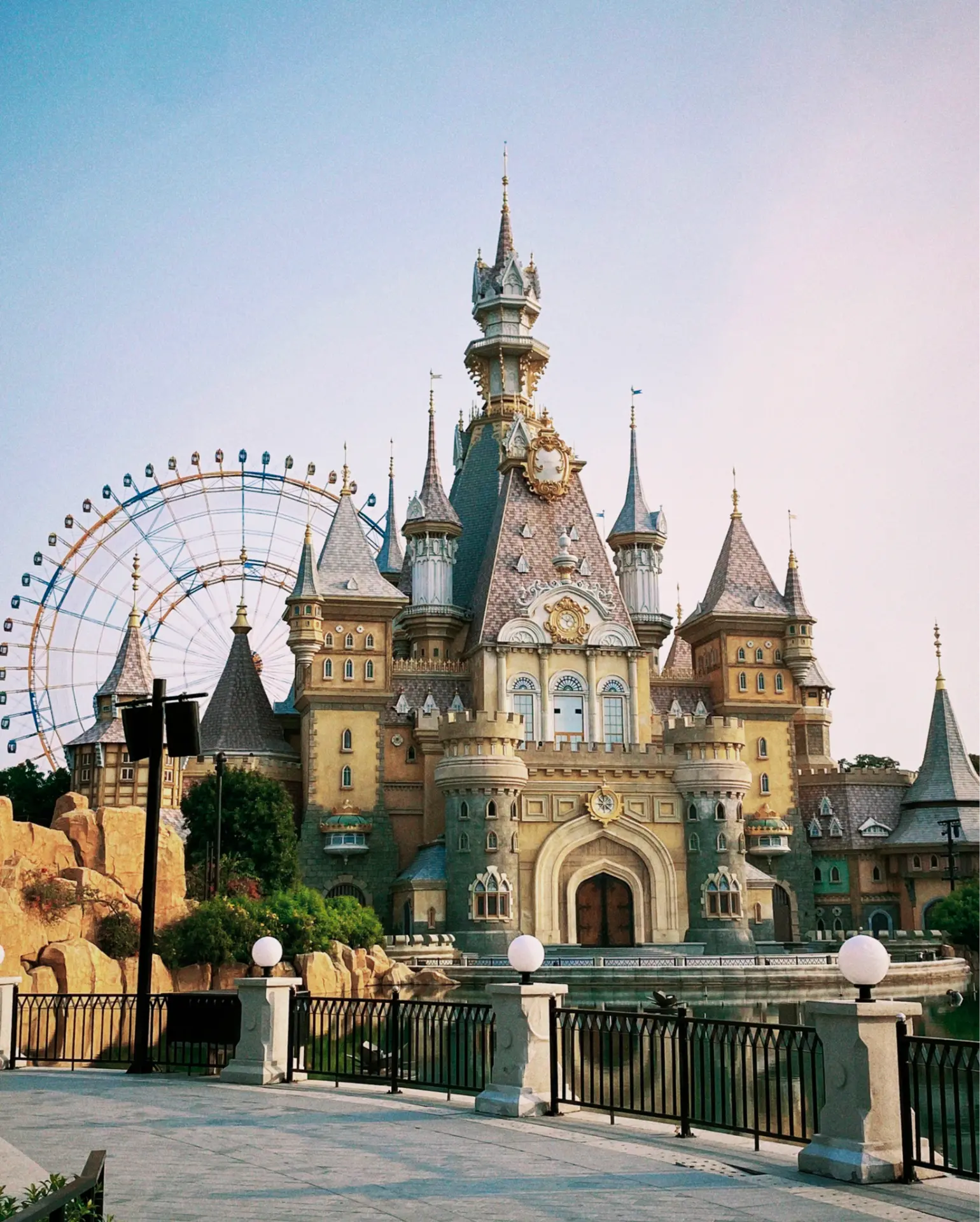 Fairy-tale castle beside a pond with a Ferris wheel behind