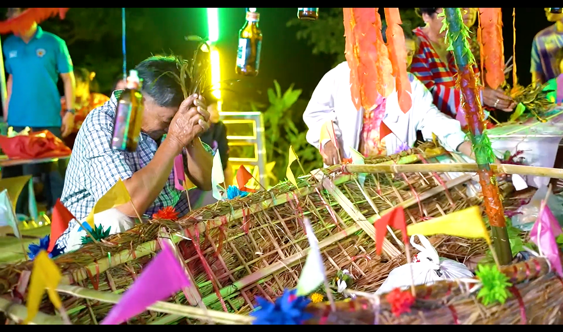 Documentary still — an elderly man praying at festival offerings