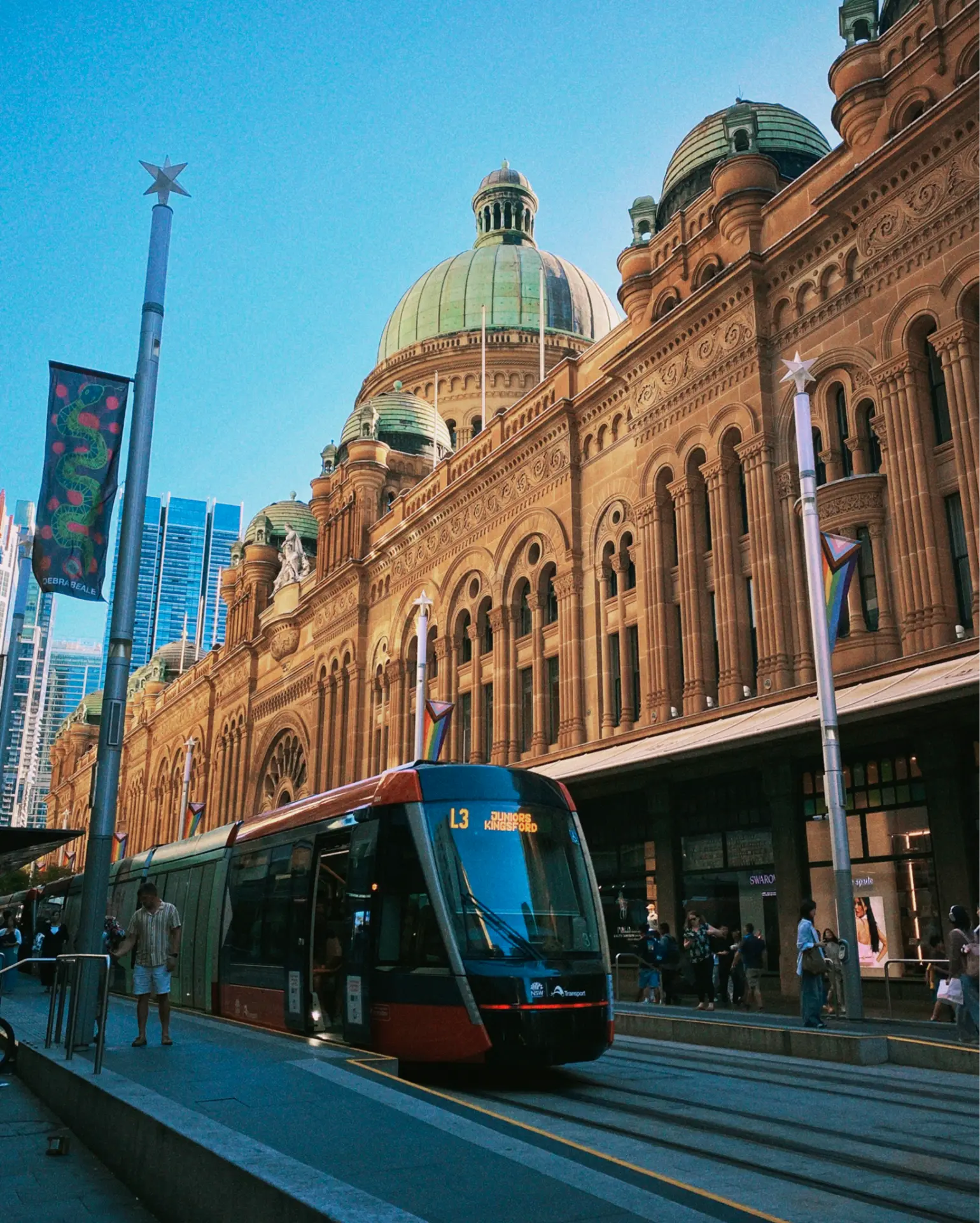 Light rail tram stopped in front of an ornate sandstone building