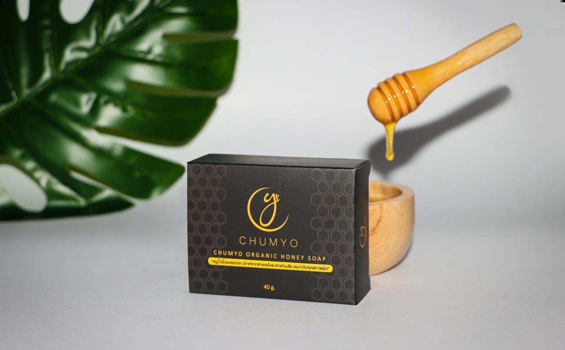 Chumyo honey soap packaging box beside a dripping honey dipper over a wooden bowl