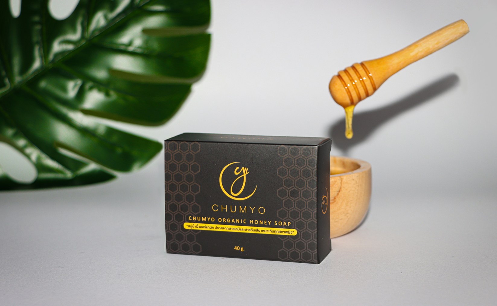 Honey dipper dripping honey over the Chumyo soap box and a wooden bowl