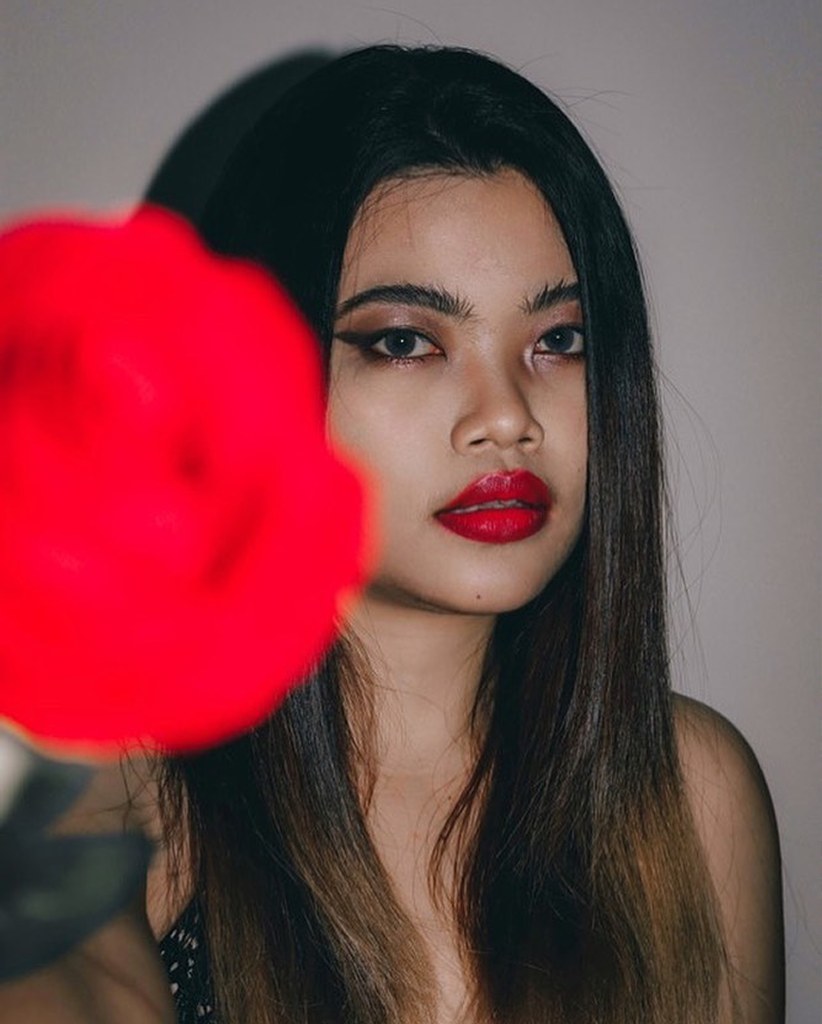 Woman holding a red rose in front of her face