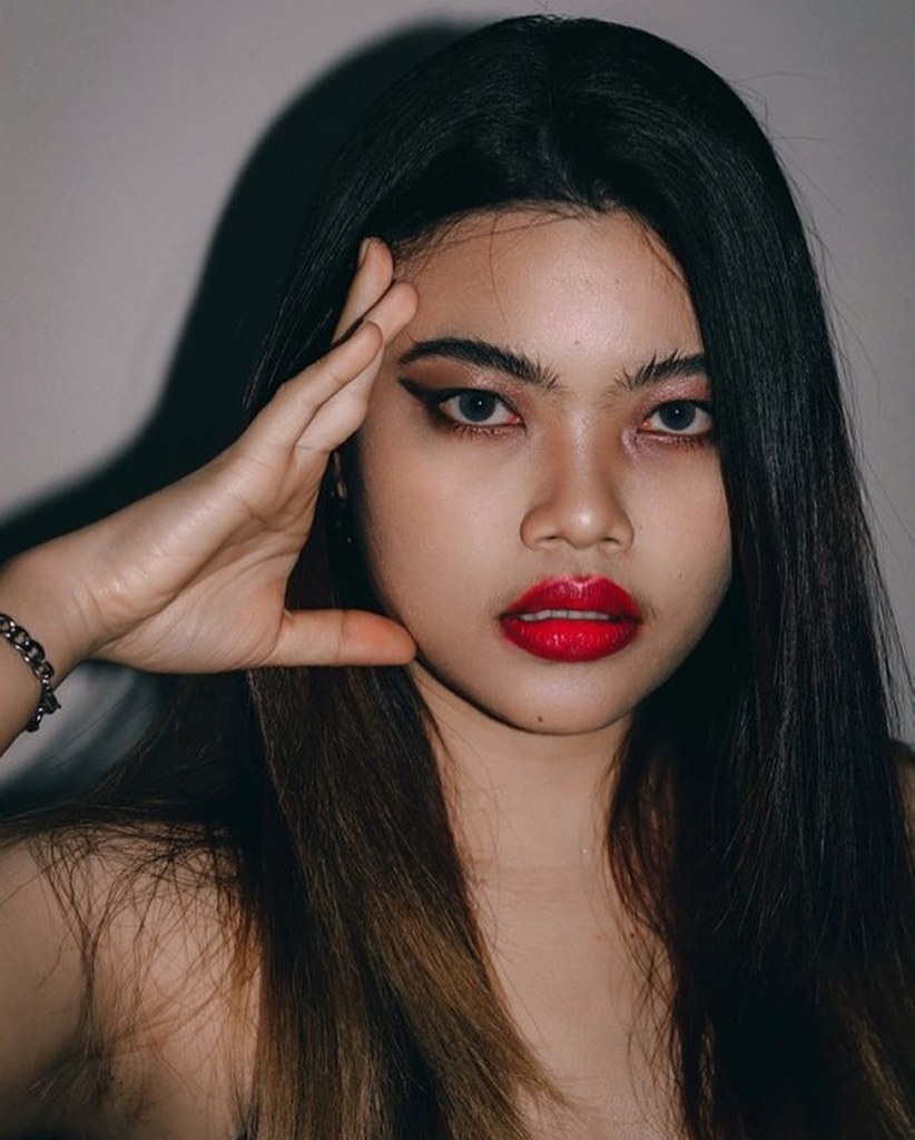 Woman covering one eye with her hand, red lips