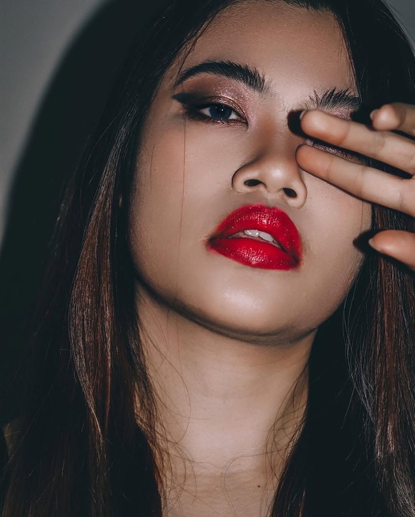 Close-up portrait of a woman with red lips and dark eye makeup